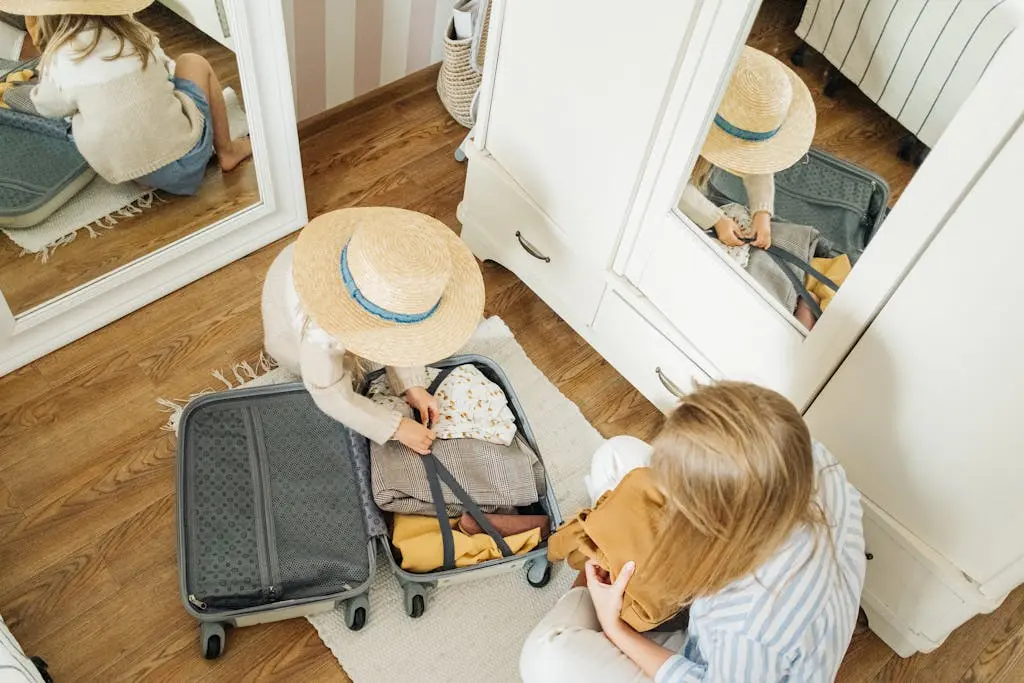 O que levar na mala? 6 Itens Indispensáveis para viajar 2 mãe com a filha pequena sentadas no chão e arrumando a mala para viajar