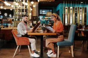 Experiência do cliente. Dois clientes sentados a mesa de um restaurante olhando o cardápio